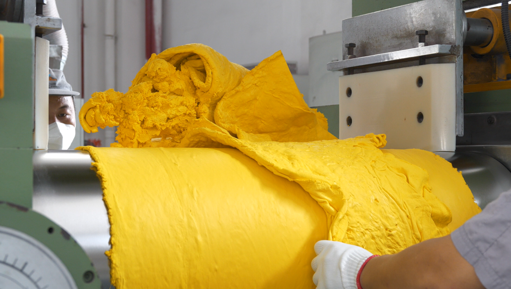 Close up shot of FKM raw gum being loaded into an industrial mixer, showing the start of the precision compounding process.